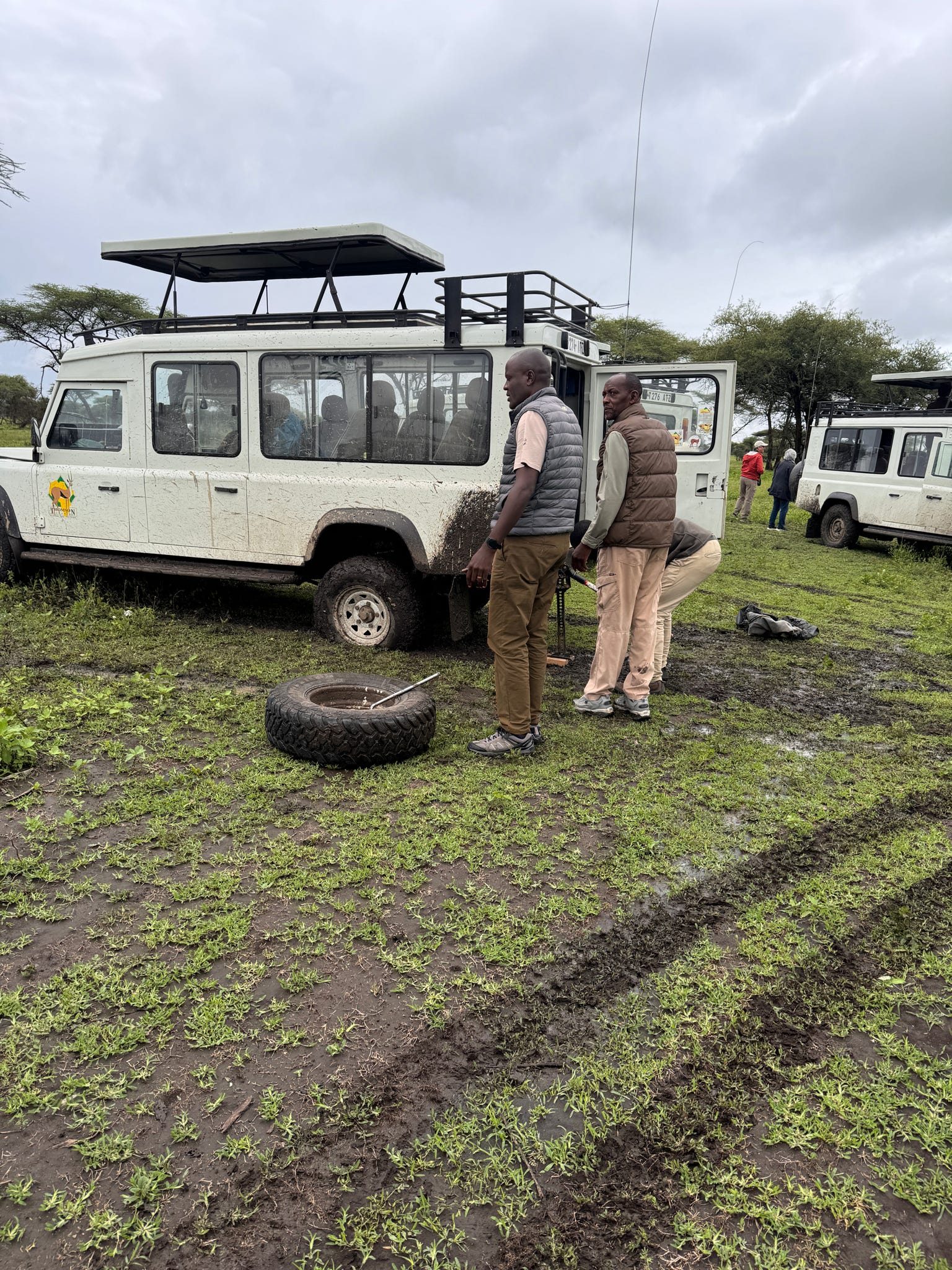 Flat tire change in the Tarangire mud — guides working in the rain