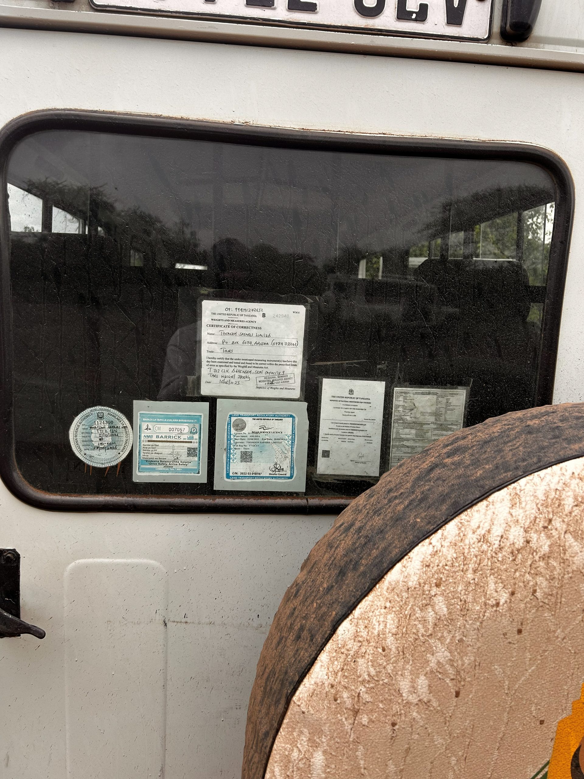 Thomson Safaris vehicle window covered in Tanzanian park permits and certificates — the paperwork that gets you in