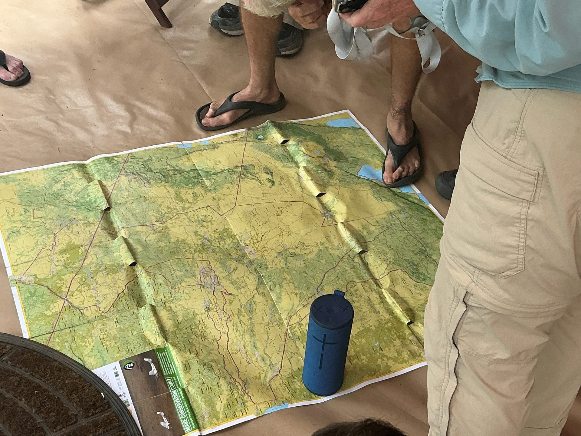 The group gathered around a large topographic map of the Ngorongoro Conservation Area spread on the dining tent floor — guides pointing out tomorrow's route